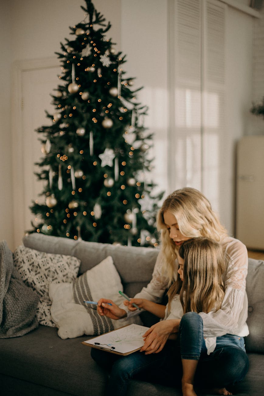 girl sitting on woman s lap while holding pen and paper